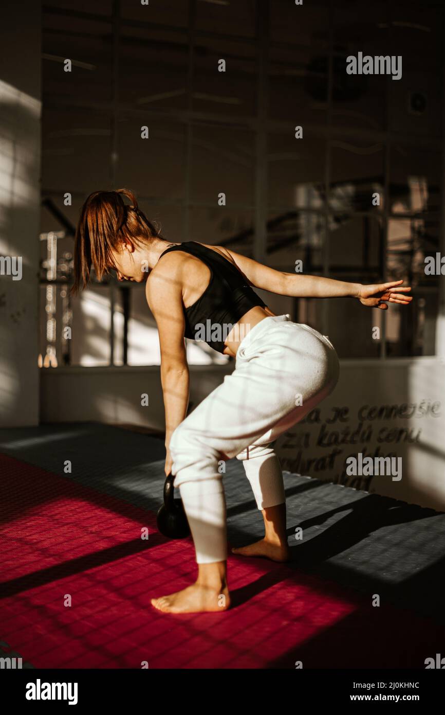 woman doing kettlebell swing. girl in the back who is practicing strength training Stock Photo