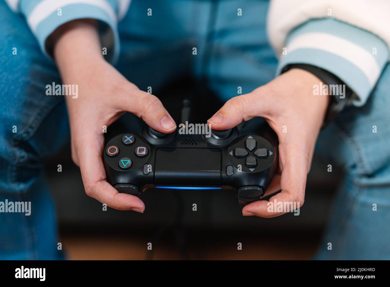 Detail shot of a young woman's hands with a video console controller playing a game. Stock Photo