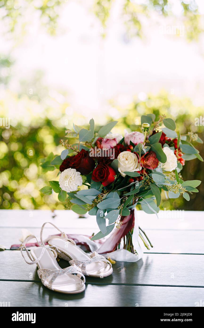 Bridal bouquet of white and red roses, peonies, branches of eucalypt tree, alstroemeria and chrysantemum with white and maroon r Stock Photo