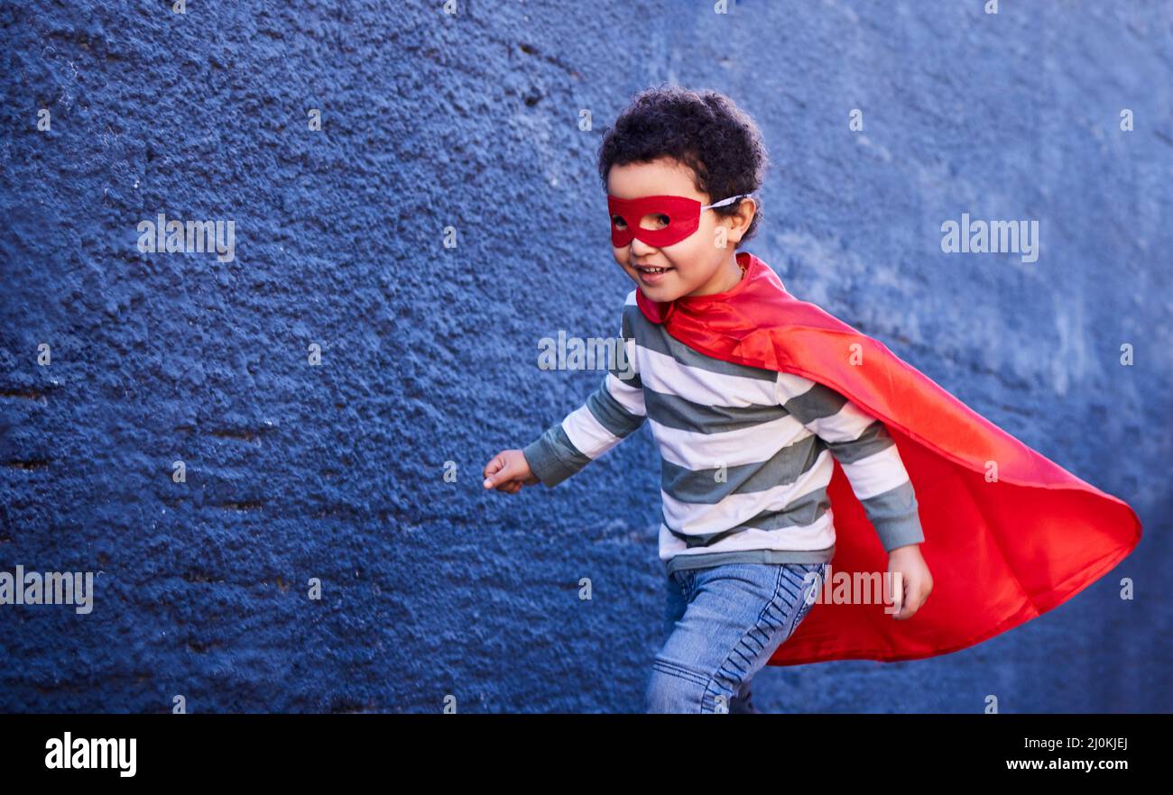 Running off to have the most fun. Shot of an adorable little boy wearing a superhero costume while playing outdoors. Stock Photo