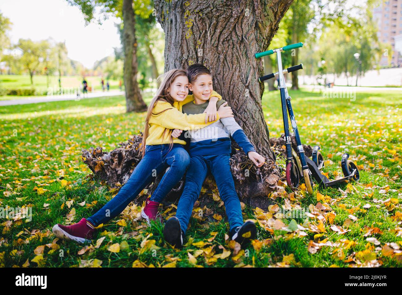 Active leisure and outdoor sports for children. Happy childhood. Boy and girl twins happily posing hugging while sitting under a Stock Photo