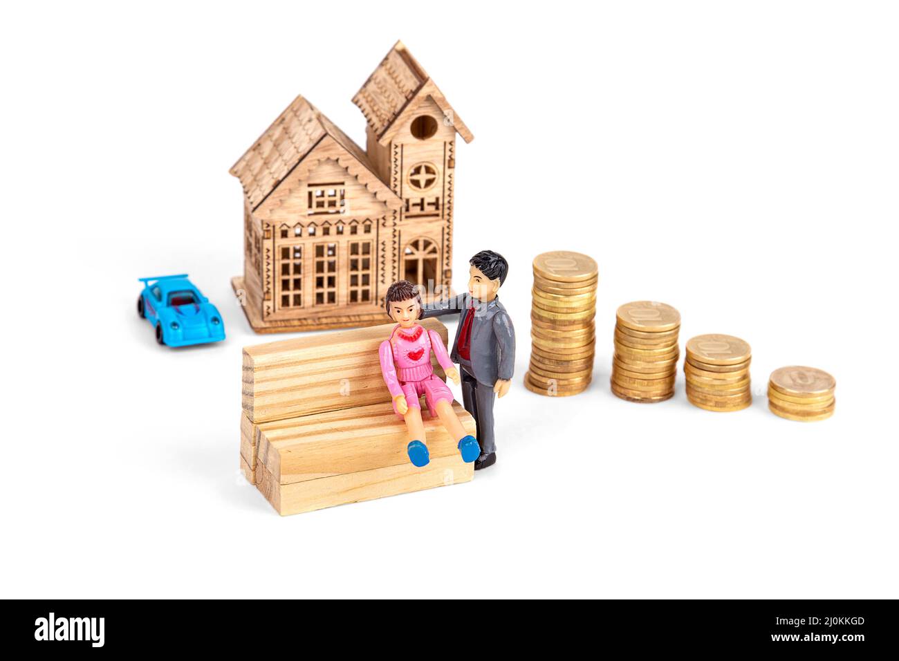 Toy figures of people, on the background of a wooden house and stacks of coins, on a white background Stock Photo
