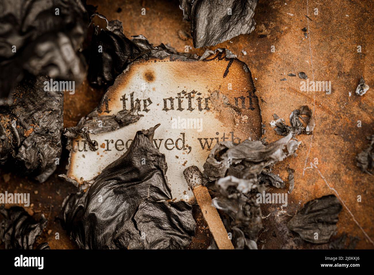Old burned paperwork surrounded by burnt paper ashes Stock Photo