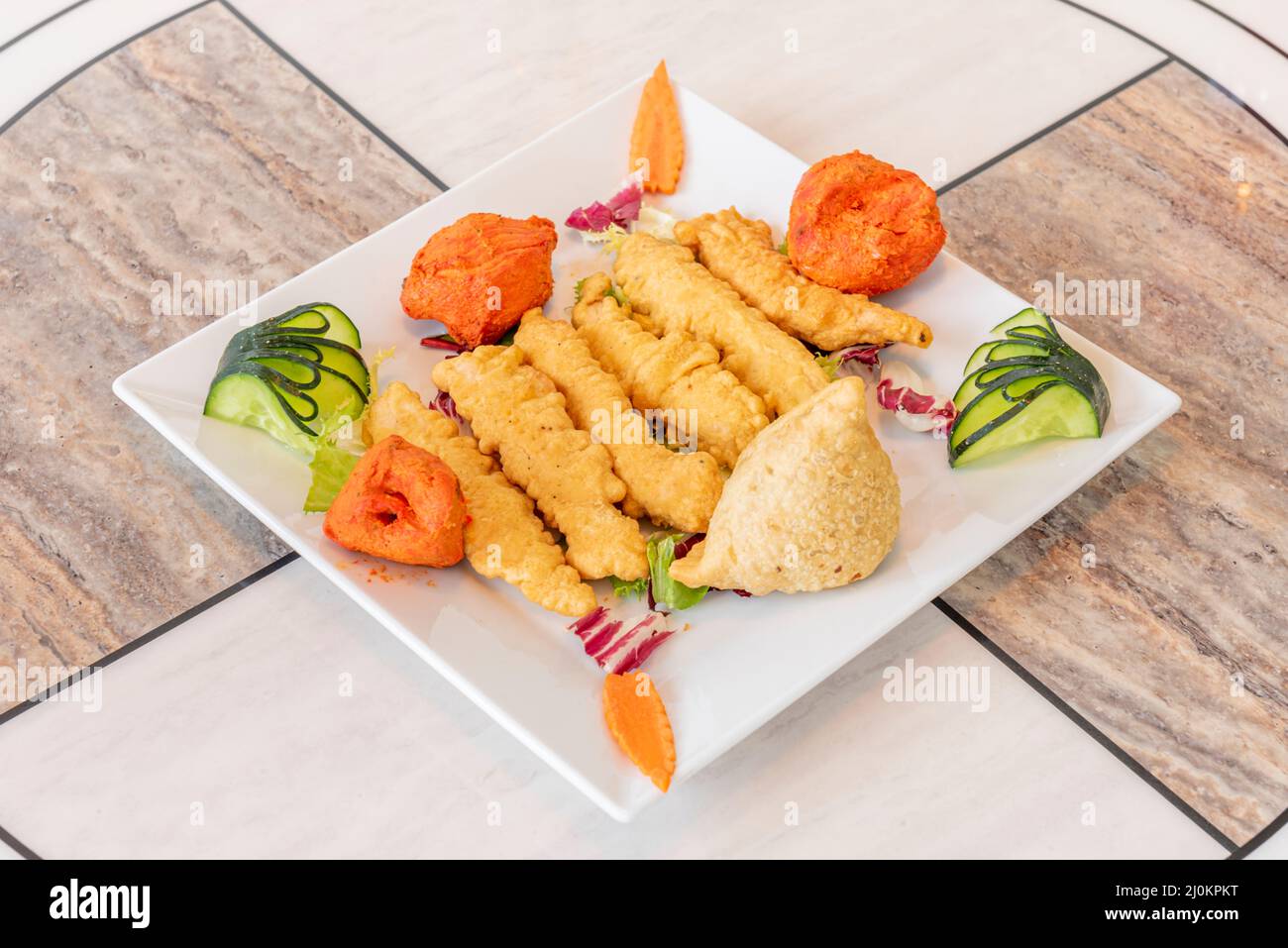 Indian appetizer platter with onion batter, chicken tikka masala pieces
