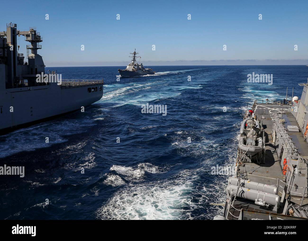 ATLANTIC OCEAN (March 17, 2022) – The Arleigh Burke-class guided-missile destroyer USS Truxtun (DDG 103), center, and the Arleigh Burke-class guided-missile destroyer USS Porter (DDG 78), right, move into position alongside the Lewis and Clark-class dry cargo ship USNS William McLean (T AKE-12), March 17. USS Porter, forward-deployed to Rota, Spain, is currently participating in Task Force Exercise in the U.S. 2nd Fleet area of operations. TFEX serves as the certification exercise for independent deploying ships and is designed to test mission readiness and performance in integrated operations Stock Photo