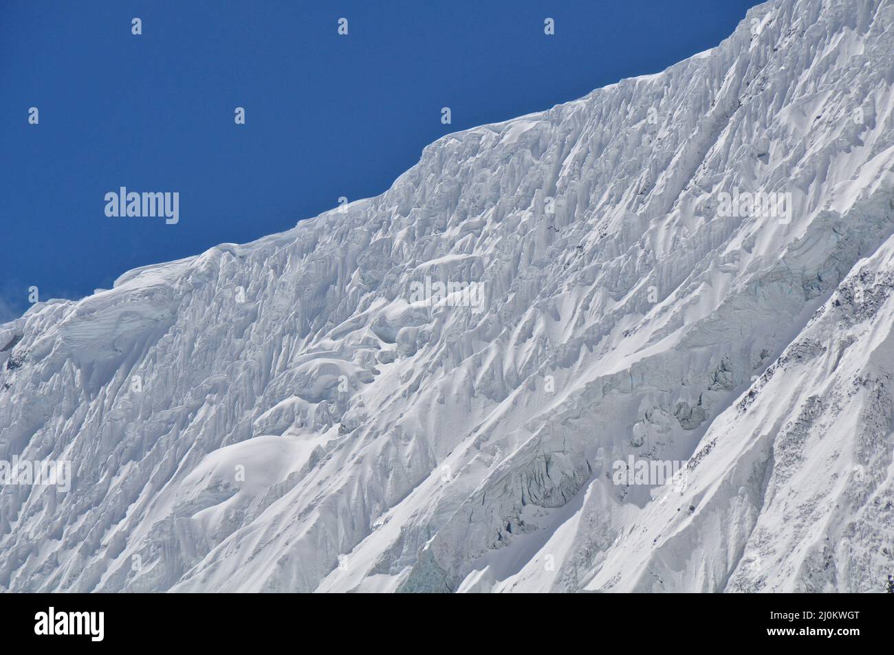 Closeup of a mountain covered in snow against a blue sky Stock Photo ...