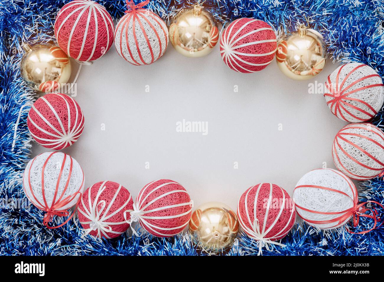 Red white and gold Christmas balls and blue tinsel are stacked in the form of a frame on a white background. Christmas mockup Stock Photo