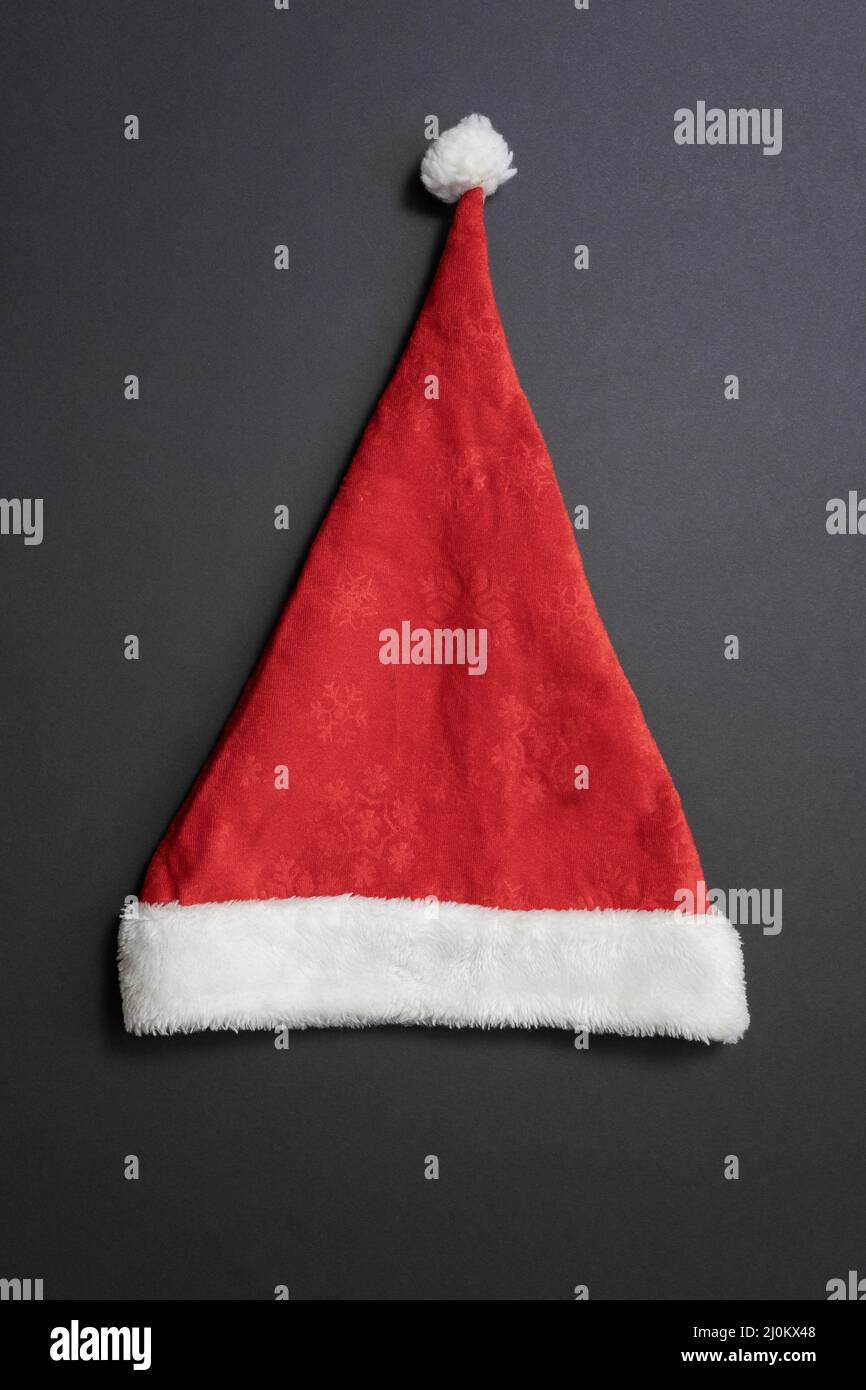 Red-white santa hat with a snowflake pattern on a dark gray background. Top view Stock Photo
