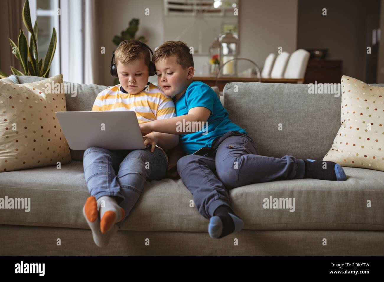two-caucasian-boys-using-laptop-sitting-on-the-couch-at-home-stock