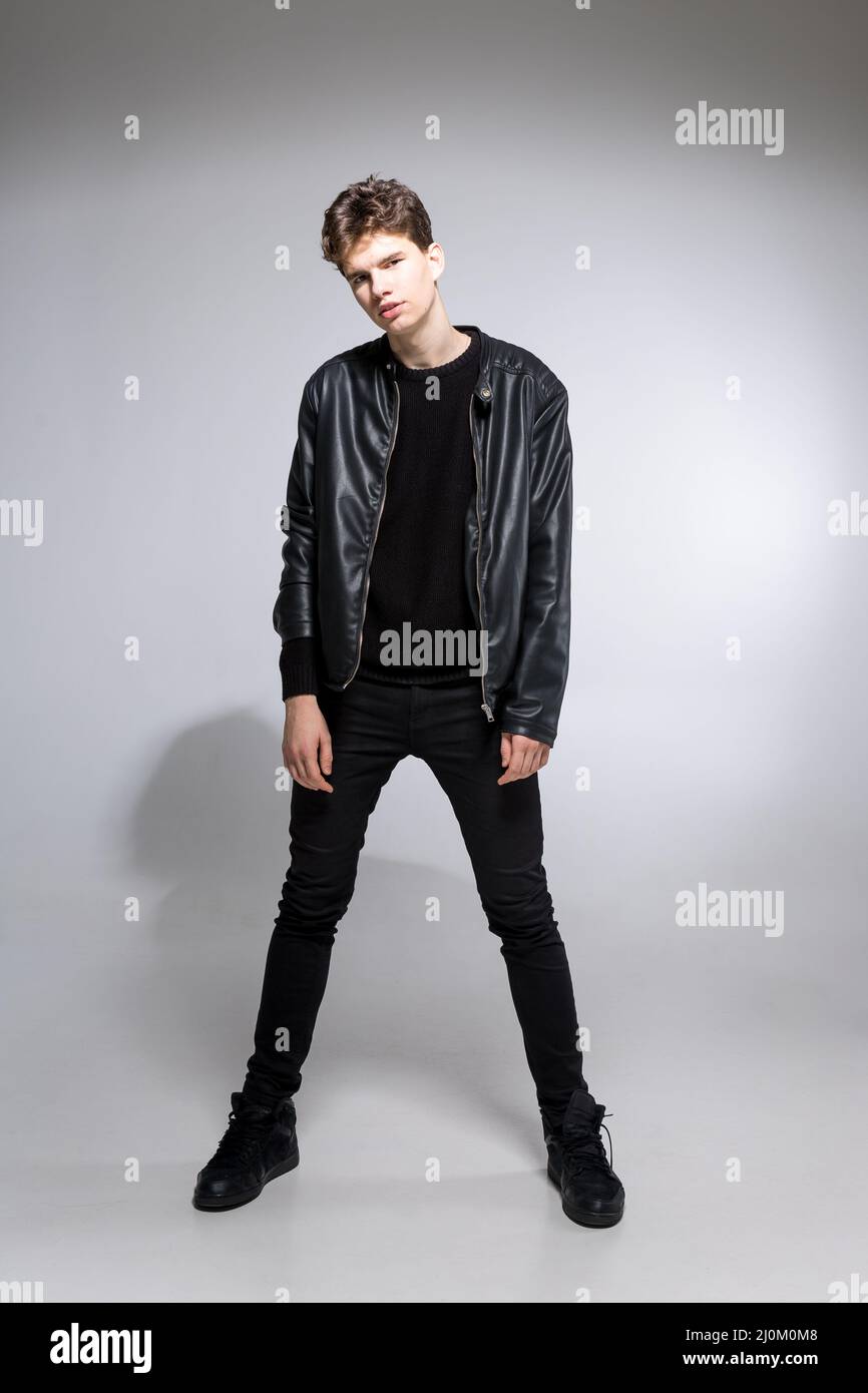 Full body image of model appearance of young fashionable guy in leather jacket and all black clothes posing on white background Stock Photo