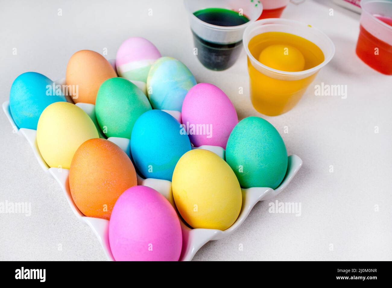 Pastel Easter eggs lying on white table. Traditional decoration Stock Photo