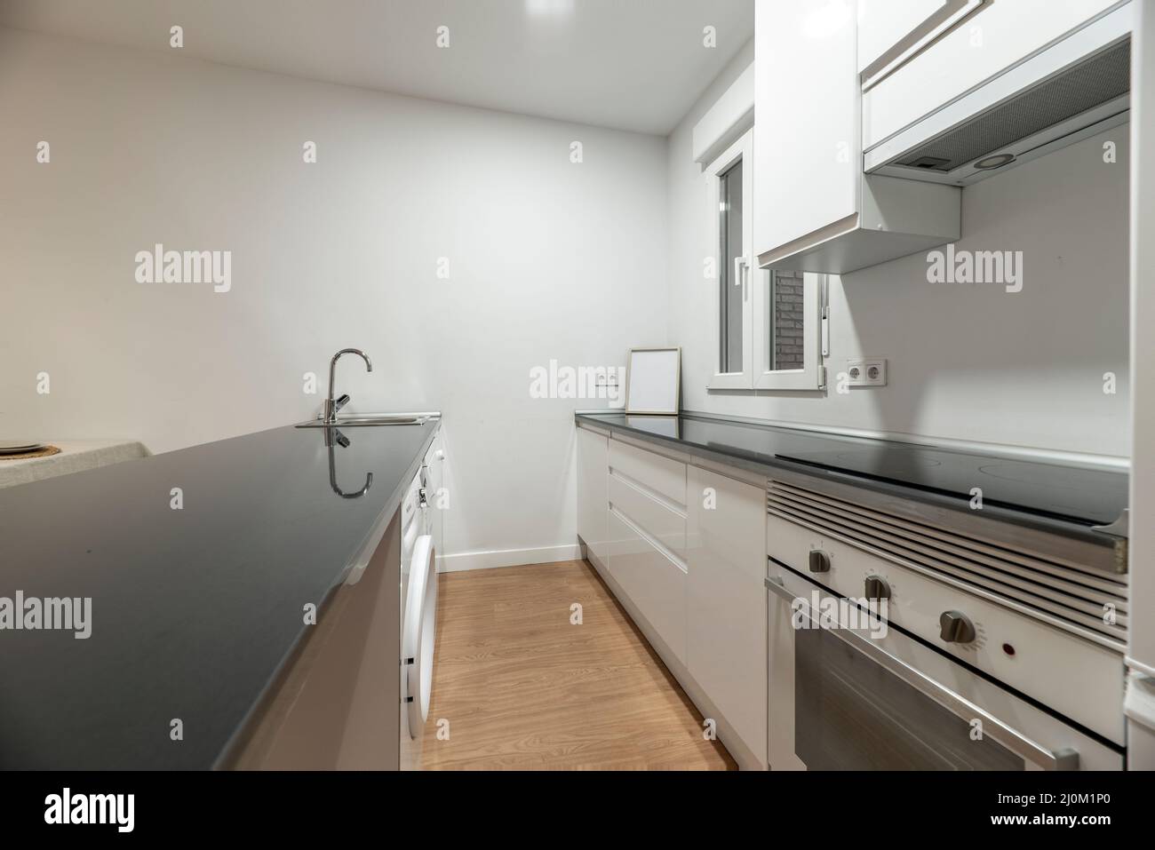 white kitchen with black countertops and white appliances and curved