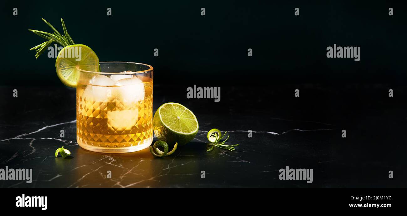 Alcoholic or non-alcoholic cocktail with lime and rosemary on dark marble table Stock Photo