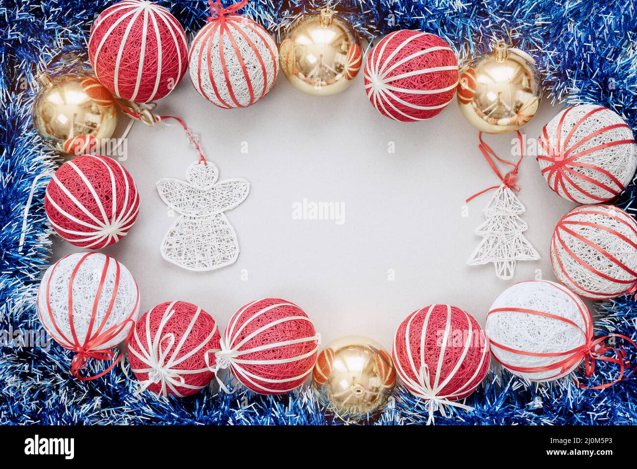 Hand-made Christmas tree decorations and blue tinsel around are laid out on a white background. Top view Stock Photo