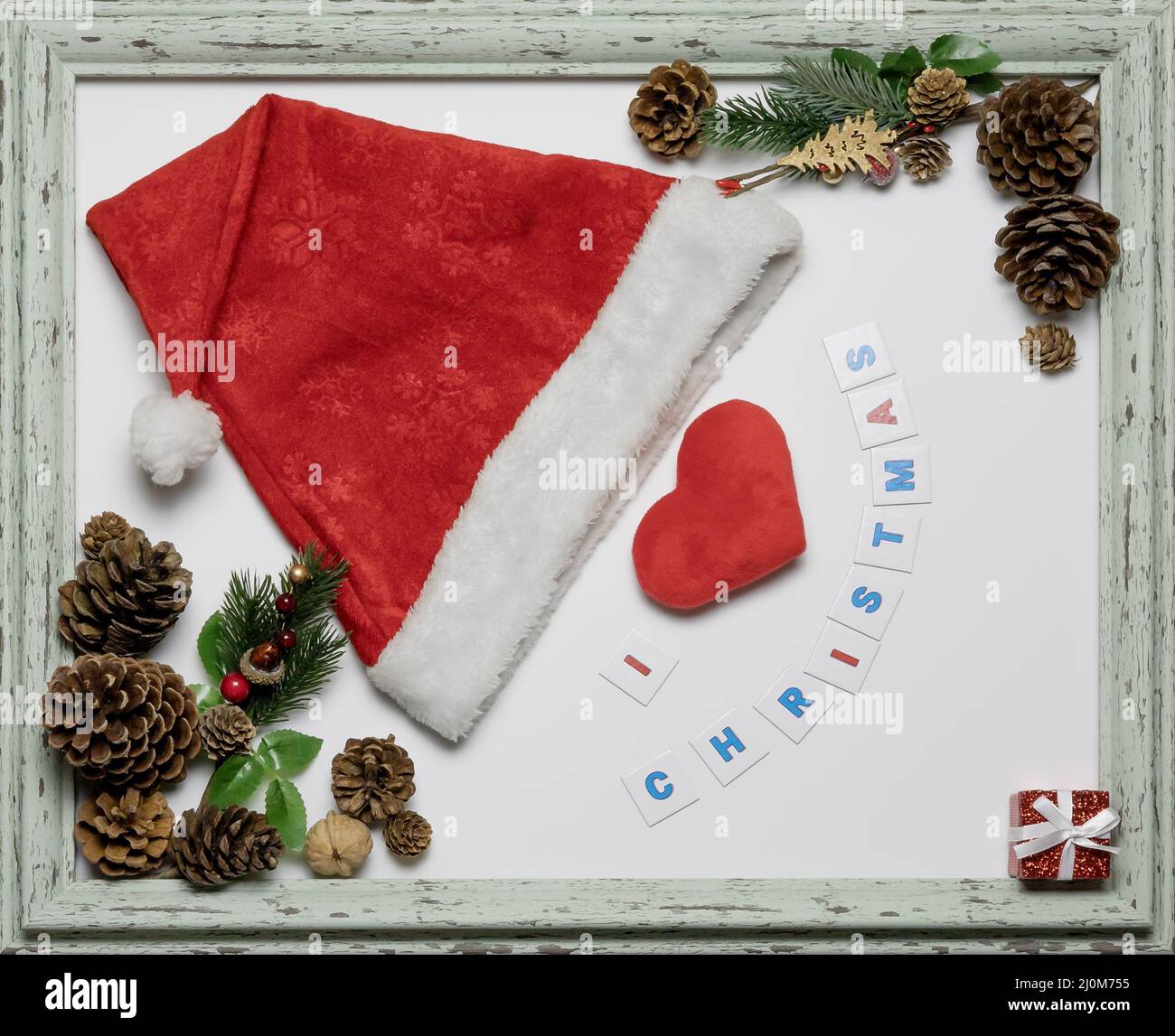 Red cap and heart in a frame with a Christmas inscription and paraphernalia. Christmas themed card. Layout composition Stock Photo