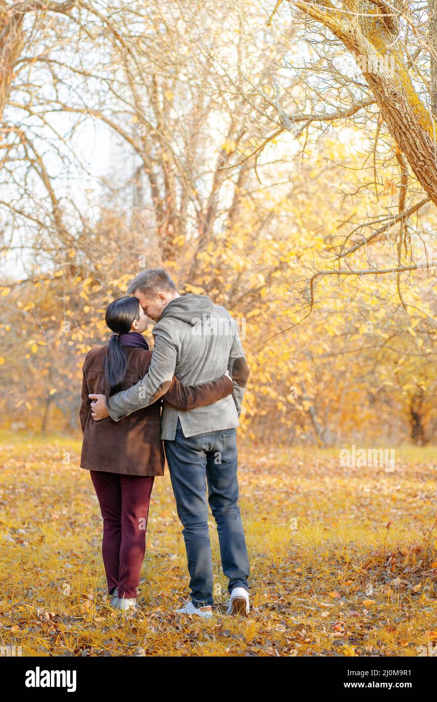 Autumn Caucasian Couple Standing Face-to-Face in a Park Full of Sun. Casual Style in Autumn Colors. Full-length. Fall Park Backg Stock Photo
