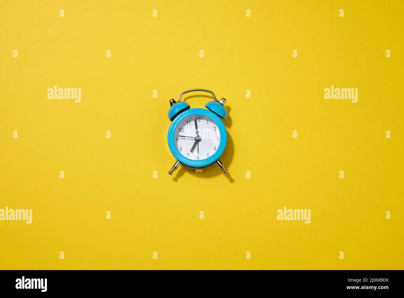 Round white alarm clock on the table. Time seven in the morning, get up early Stock Photo