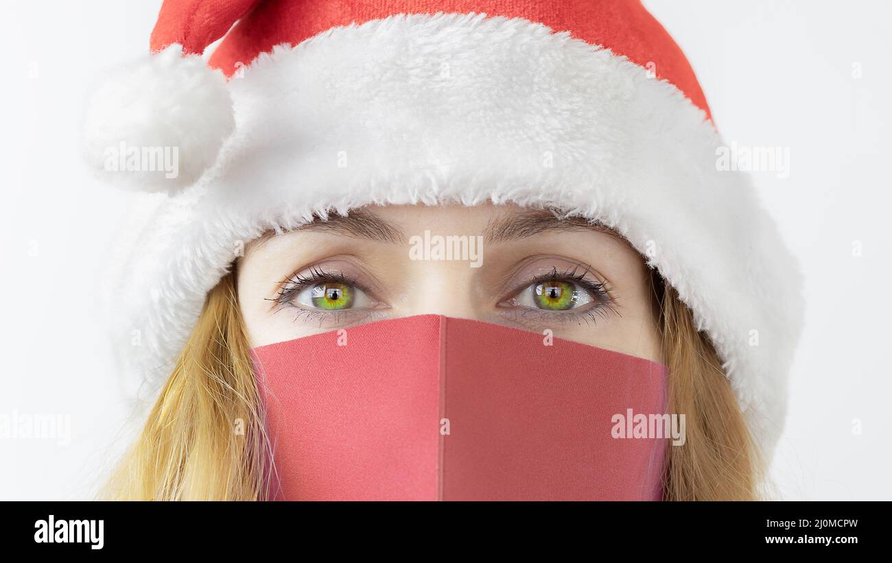 Lady in protective mask and santa hat. Lady santa. Virus protection at Christmas. Viral new year Stock Photo