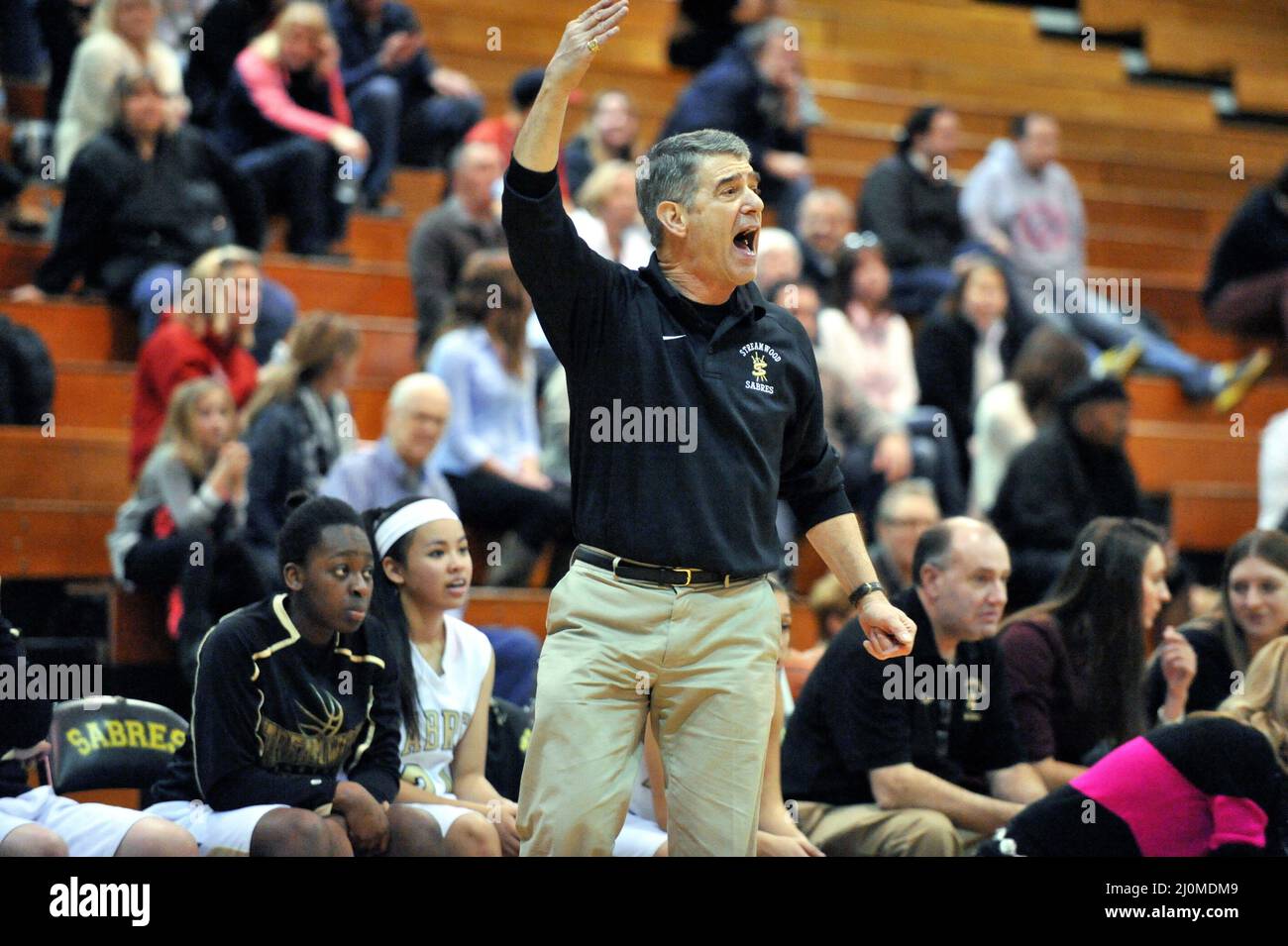 USA. High school basketball coach yelling at an official in reaction to a call on the court. Stock Photo