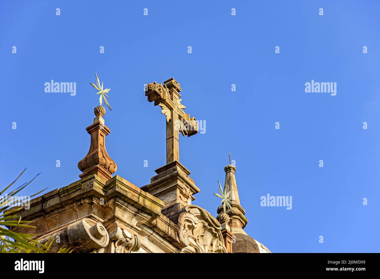 Crucifix and ornaments on top of the facade of an old and historic baroque church Stock Photo