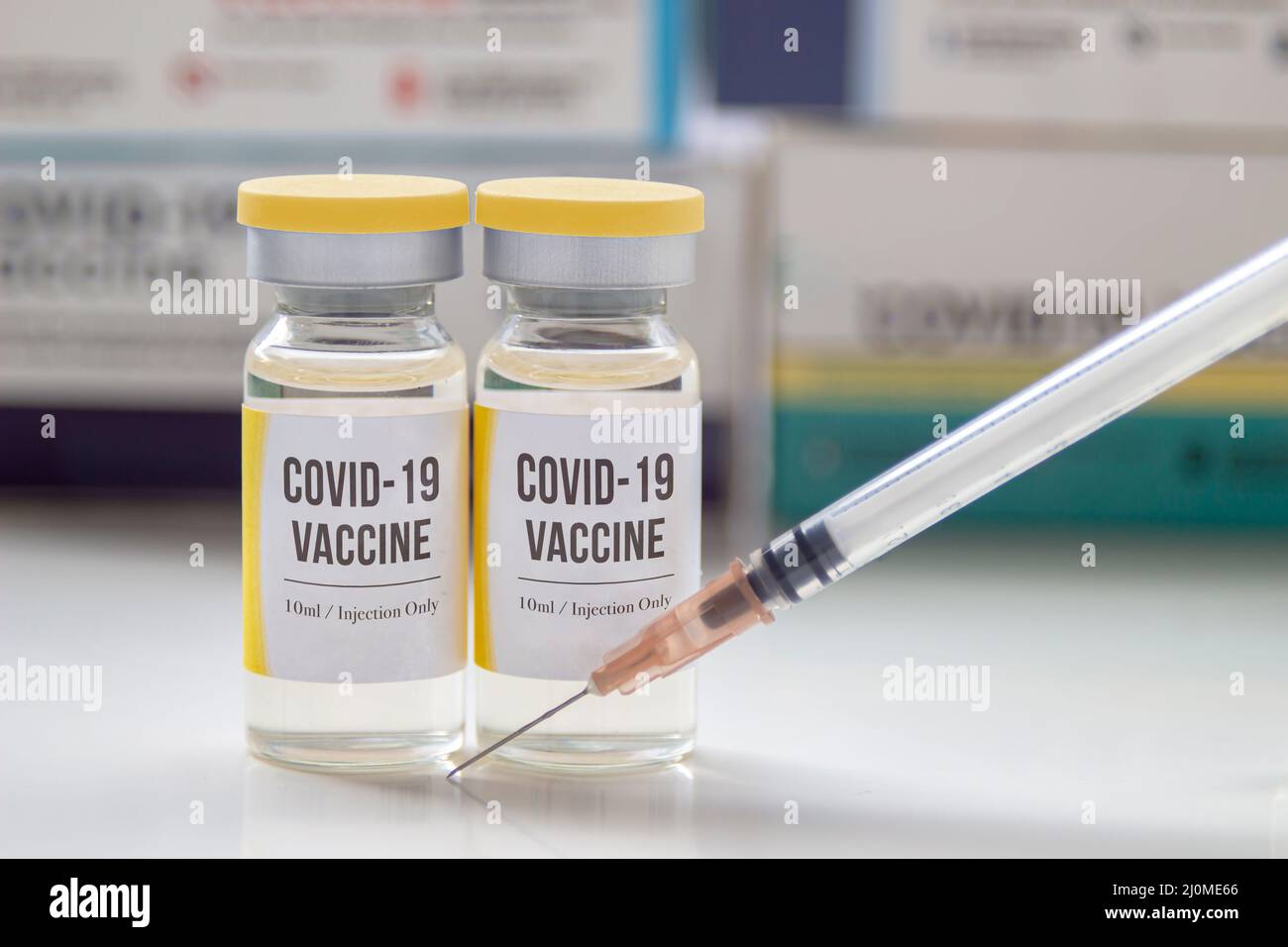 A couple of Covid-19 vaccines with a syringe and medicine boxes on the background. Stock Photo