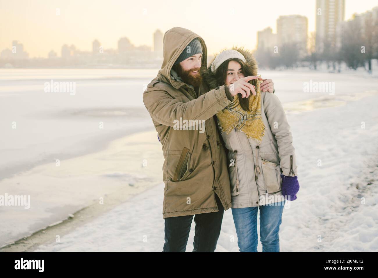 Theme love and date on nature. A young Caucasian heterosexual couple guy and girl walk in the winter along a frozen lake in wint Stock Photo