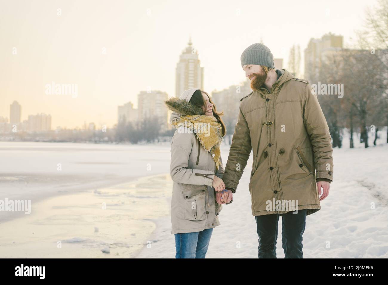 Theme Christmas holidays winter new year. Young stylish Caucasian loving couple Heteresexual walking on the shore of a frozen la Stock Photo