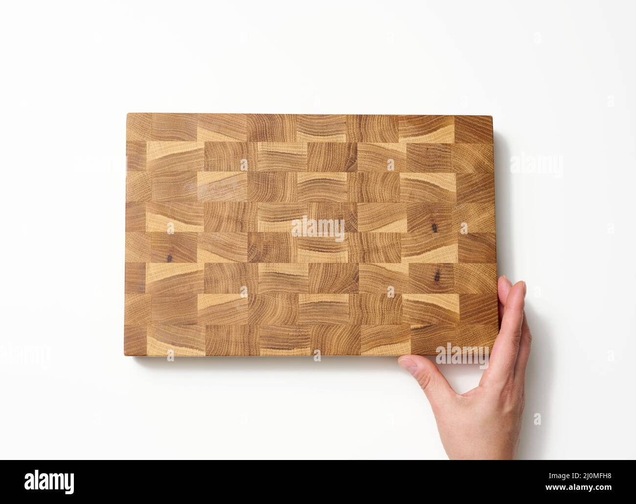 Female hands hold empty rectangular brown wooden chopping board on white background Stock Photo