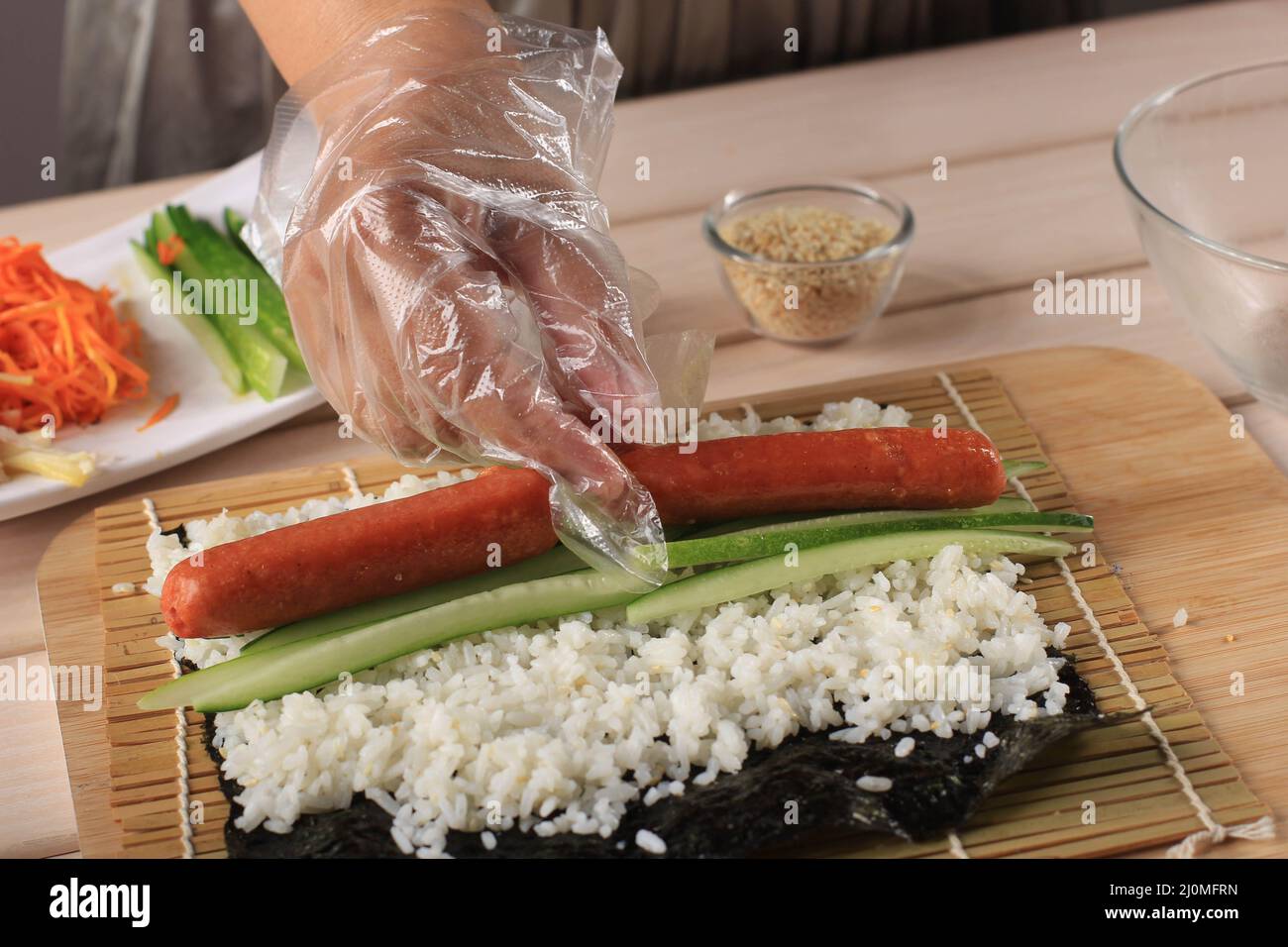 Gimbap is a Korean food made from steamed White Rice and Various other Ingredients, Rolled in Gim. Making gimbab, Put Sausage Stock Photo