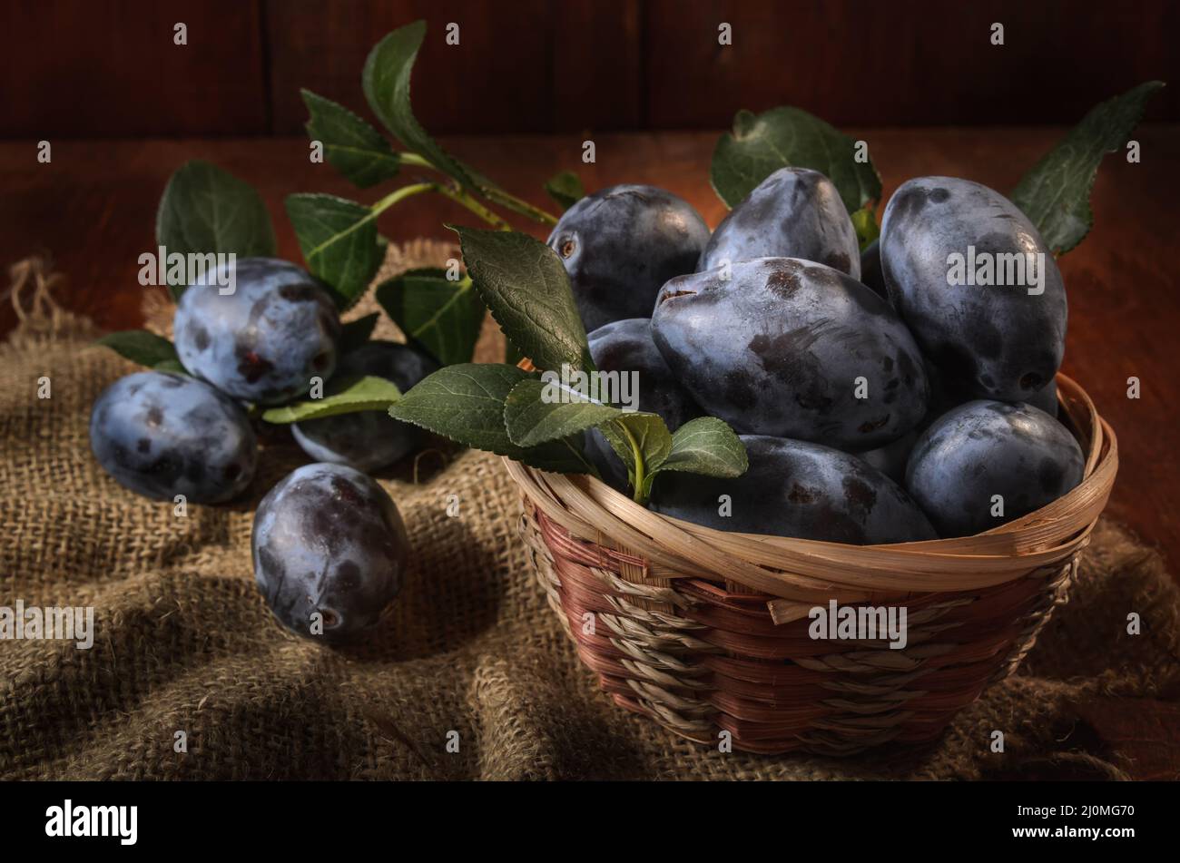 Plum in a basket on a dark wooden background in a rustic style Stock Photo