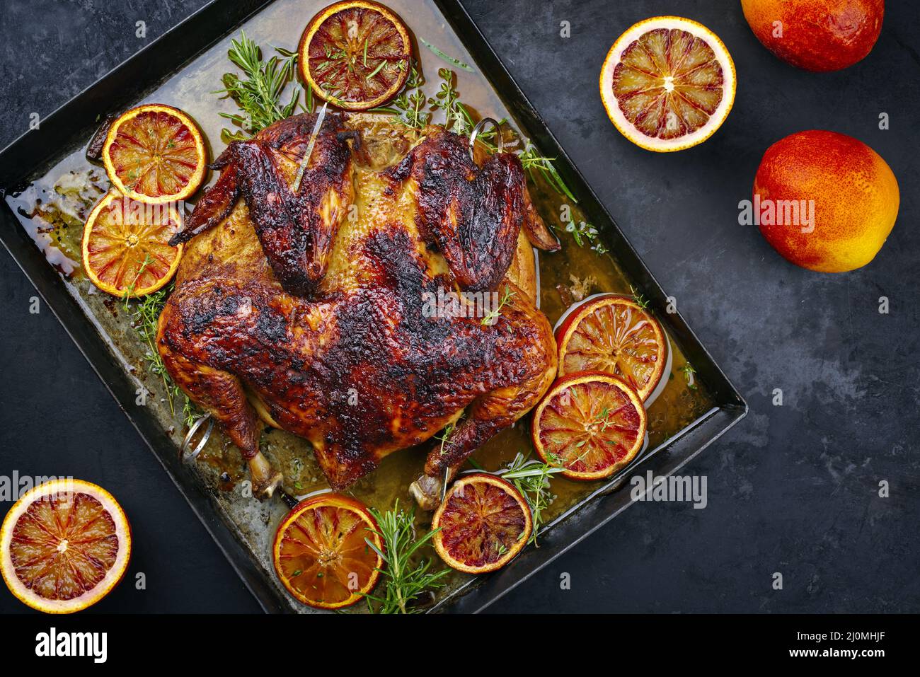 Traditional barbecue spatchcocked chicken al mattone chili with orange slices and herbs served as top view on an old rustic meta Stock Photo