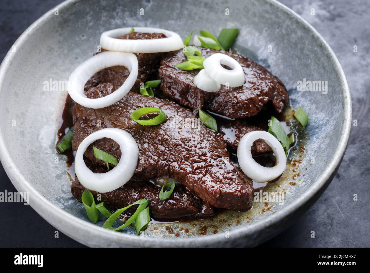 Modern style traditional Cuban dry aged angus bistec encebollado steak with onion rings in soy sauce served as close-up in a Nor Stock Photo