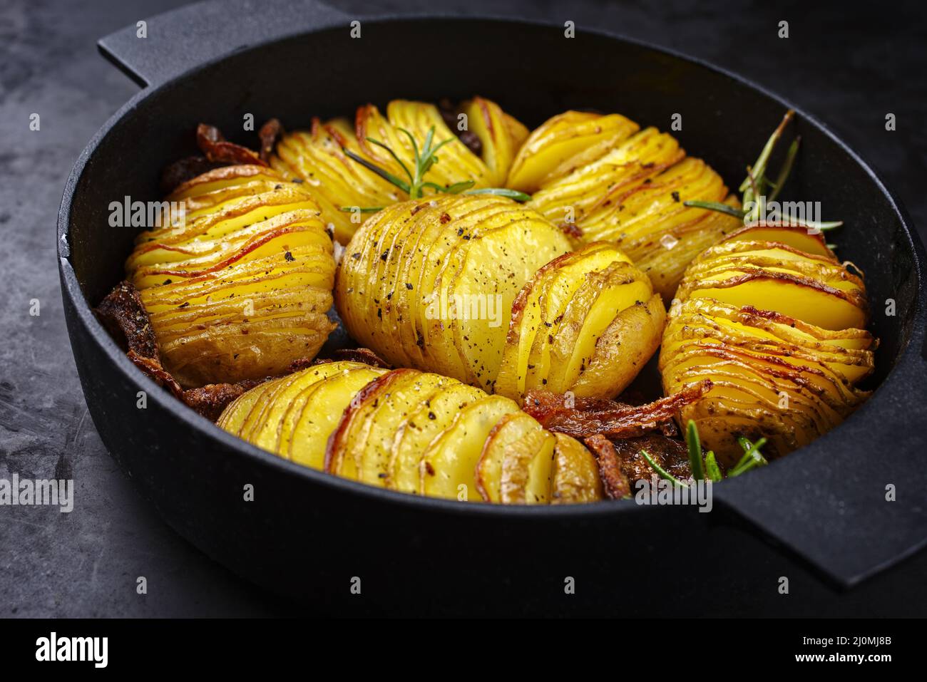 Modern style traditional potato chips with roasted onion rings and herbs served as top view in a design skillet Stock Photo