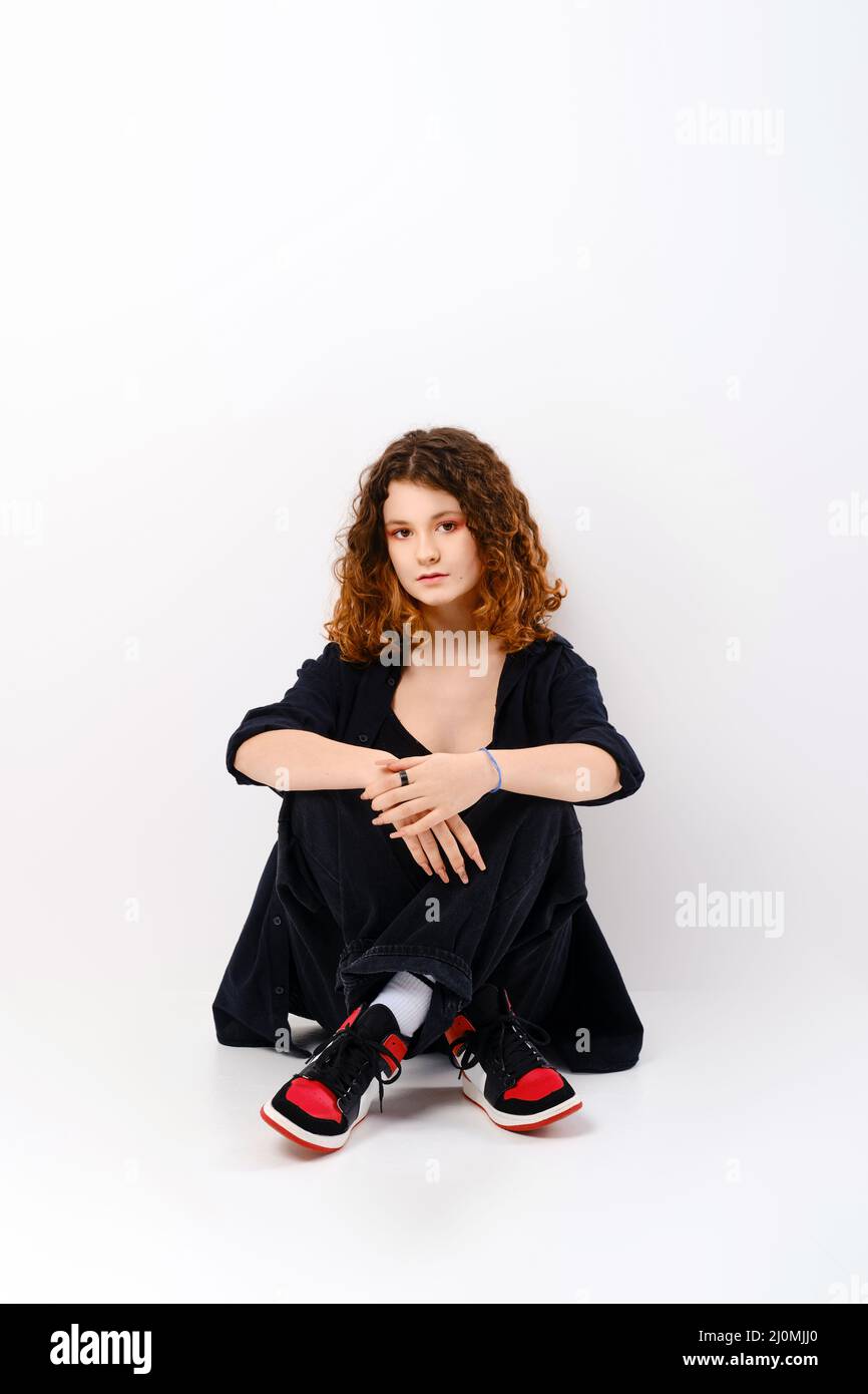 Cute girl sitting in studio on the floor with crossed legs Stock Photo ...