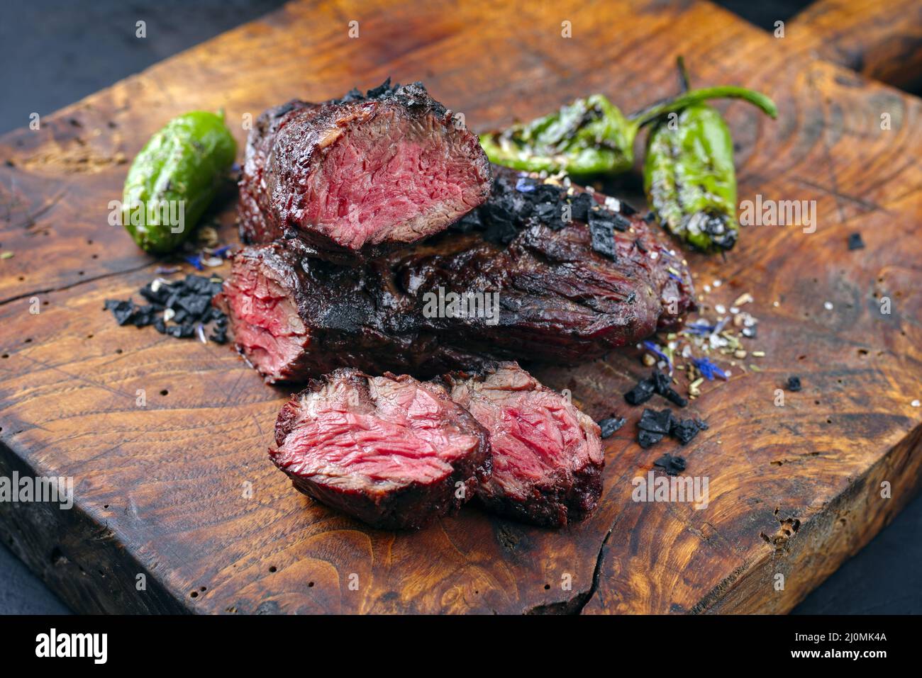 Traditional barbecue wagyu onglet steak with green chili and spices served as close-up on a rustic wooden board Stock Photo