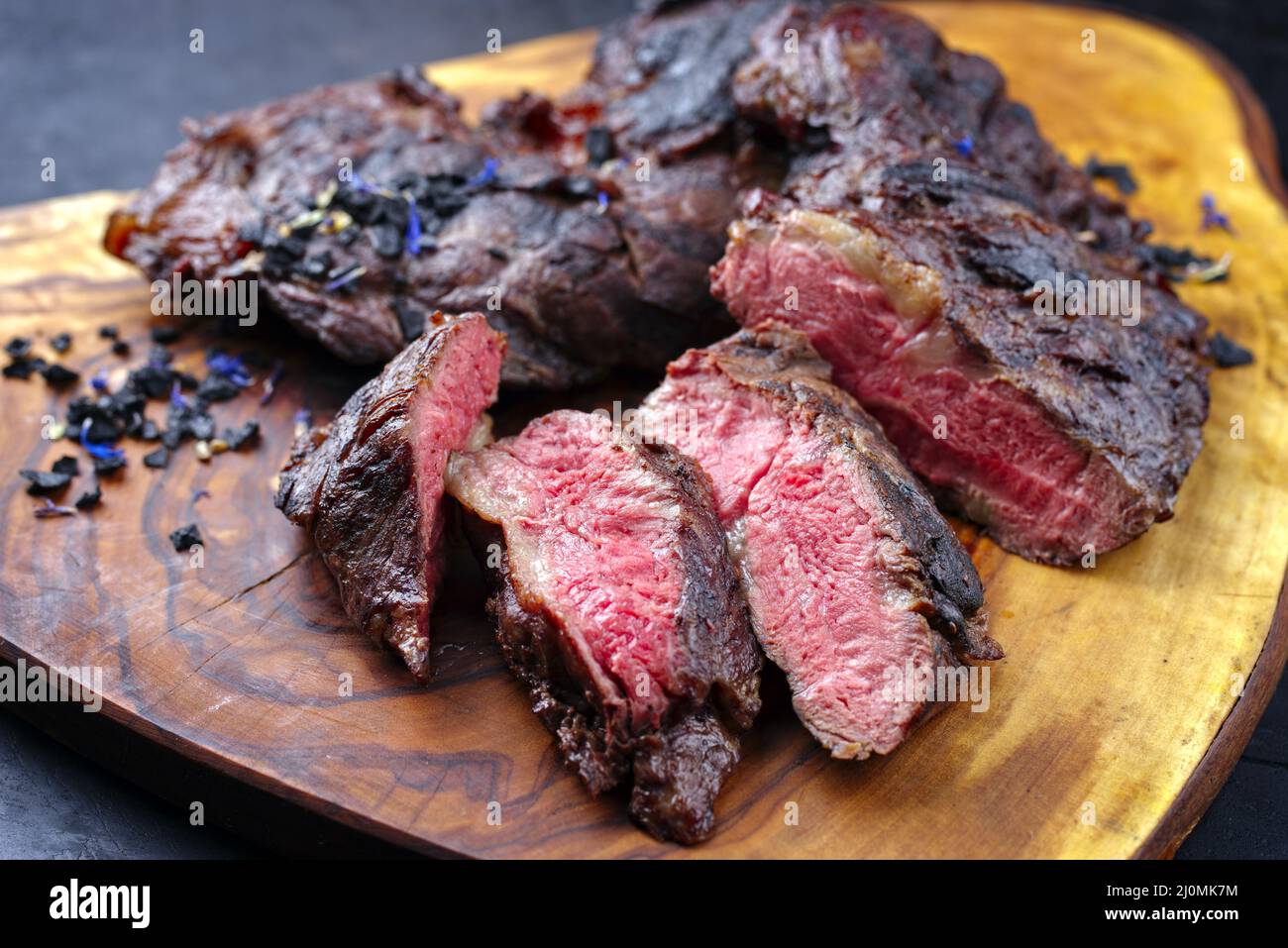 Traditional barbecue wagyu spider beef steak with black salt and spices served as close-up on a rustic wooden board Stock Photo
