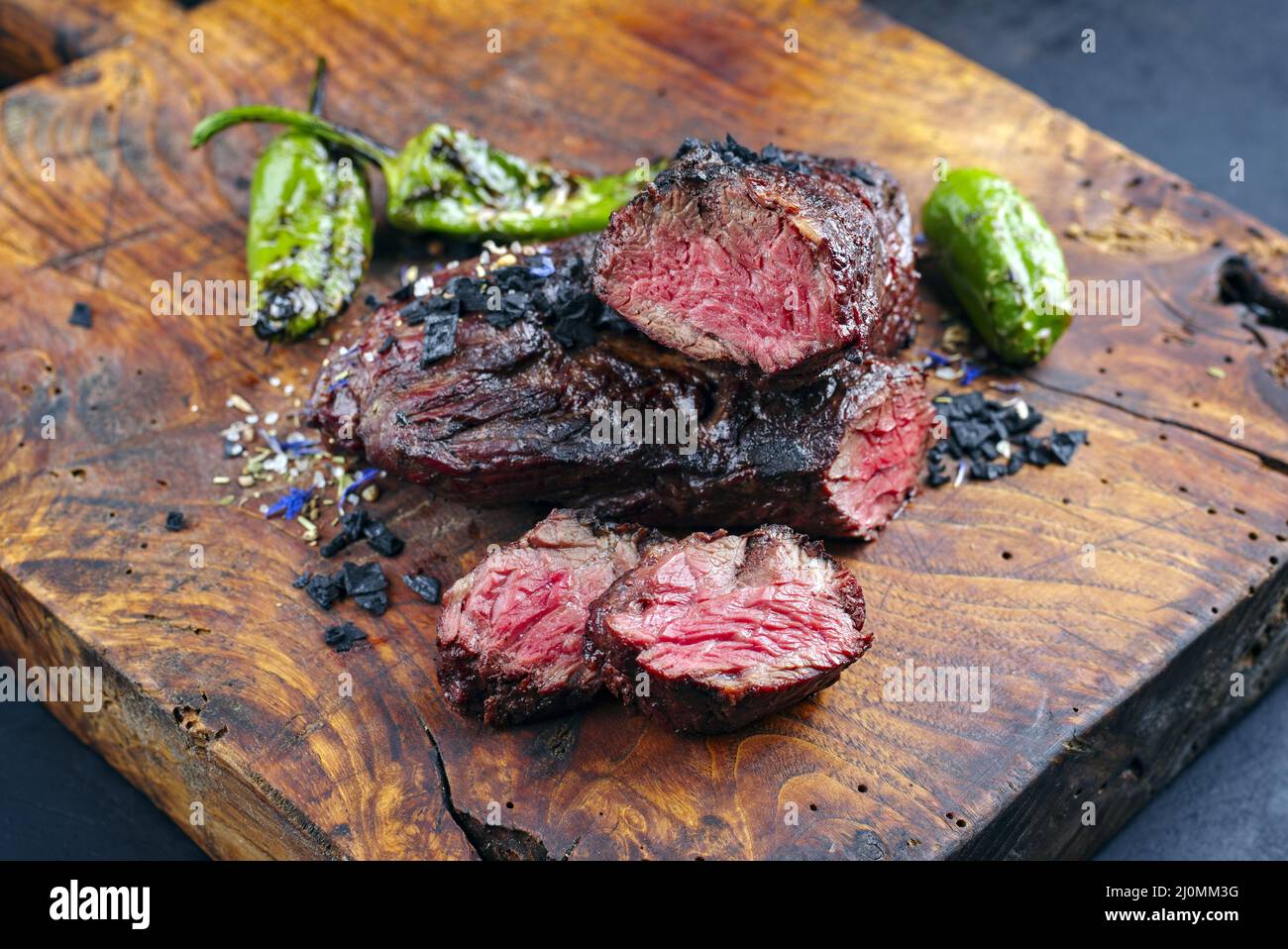 Traditional barbecue wagyu onglet steak with green chili and spices served as close-up on a rustic wooden board Stock Photo