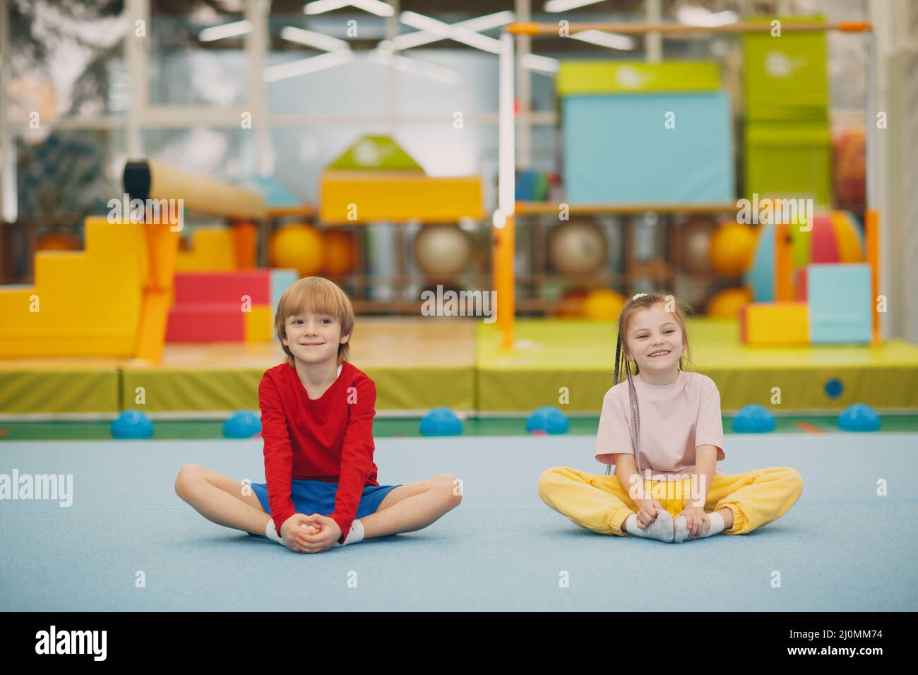 Kids doing stretching exercises in gym at kindergarten or elementary school. Children sport and fitness concept. Stock Photo