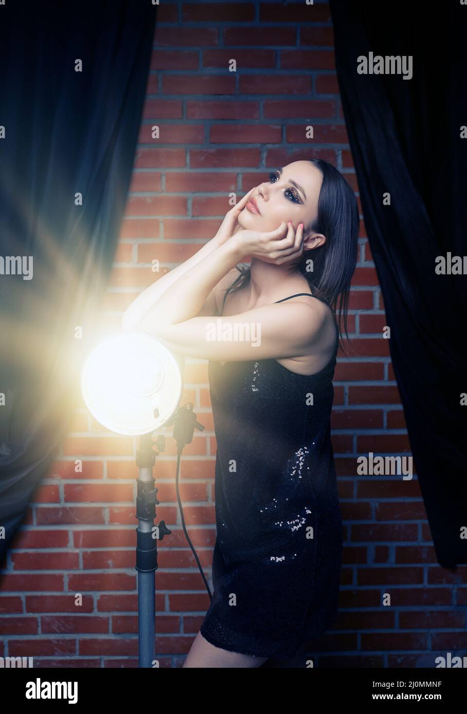 Beautiful young woman in black dress with shining face makeup Stock ...