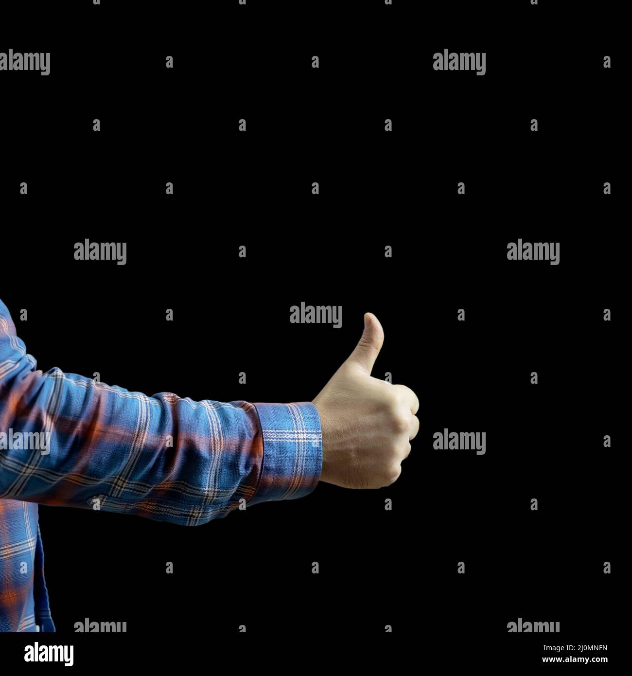 A man's hand in a checkered sleeve shows a thumb up on a black background. Gesture cool Stock Photo