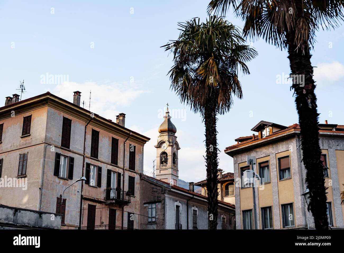 Bell tower among old houses and palm trees in the town of Menaggio. Lake Como, Italy Stock Photo