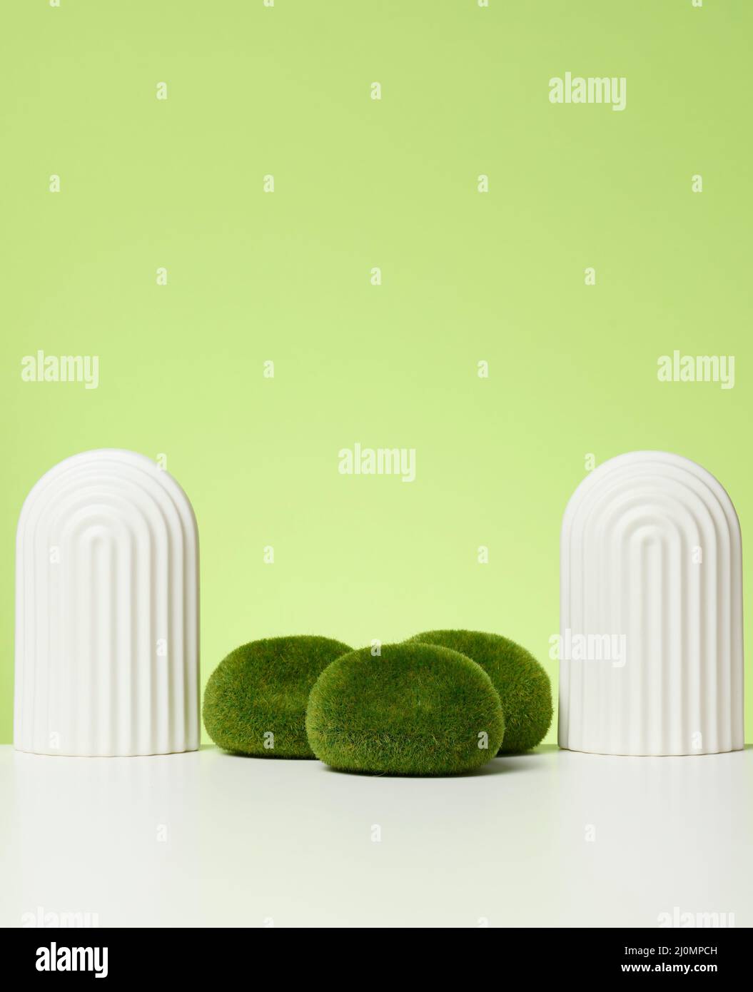Podium with moss and arches to showcase cosmetics, products and other goods. Green background Stock Photo