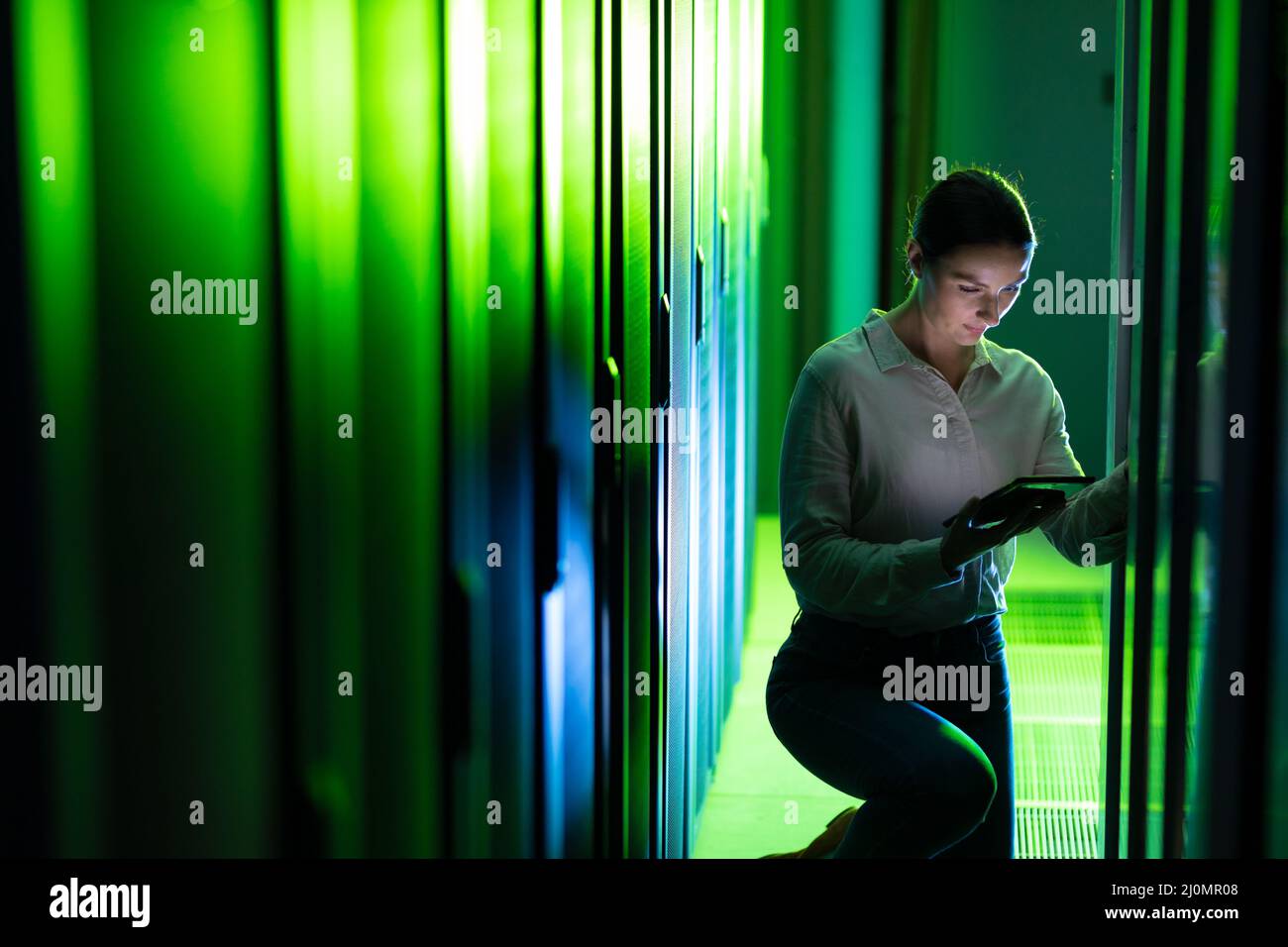 Caucasian female engineer using digital tablet while inspecting in computer server room Stock Photo