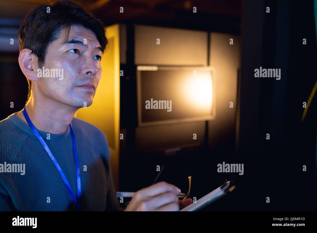 Asian male engineer writing on clipboard while inspecting in computer server room Stock Photo