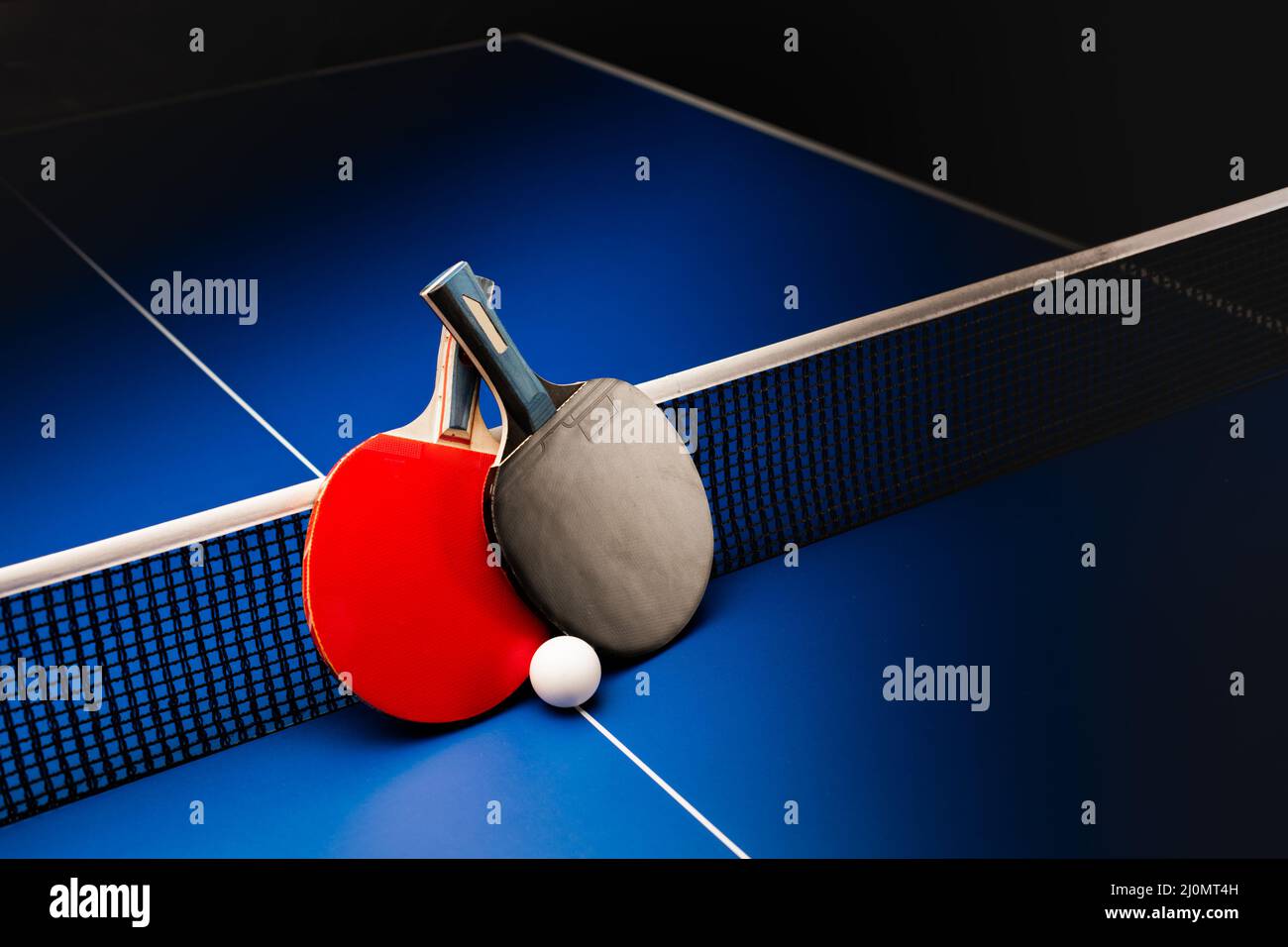 Two table tennis rackets and balls on a blue table with net Stock Photo