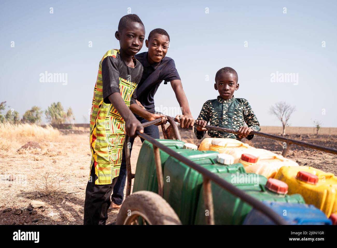 African young boys transporting water on a pushcart for the needs of their community,water scarcity concept. Stock Photo