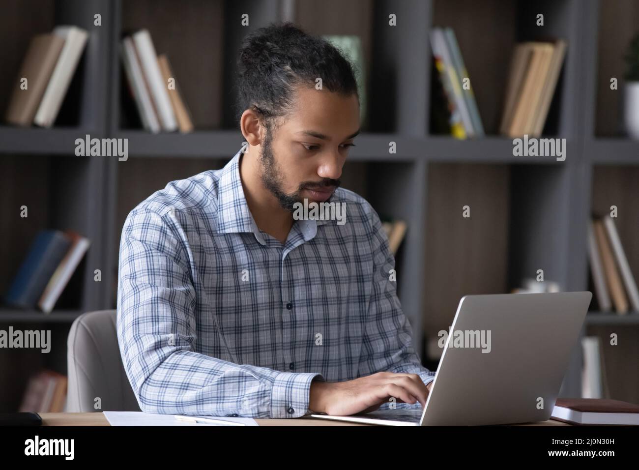 Serious worker guy working on online project at laptop Stock Photo