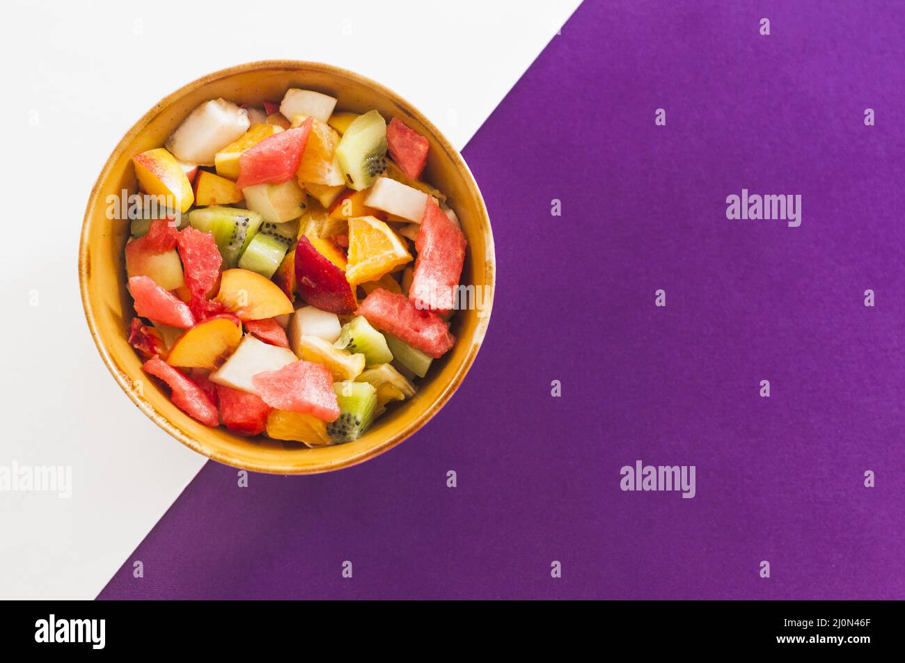 Bowl fruit salad white purple background Stock Photo