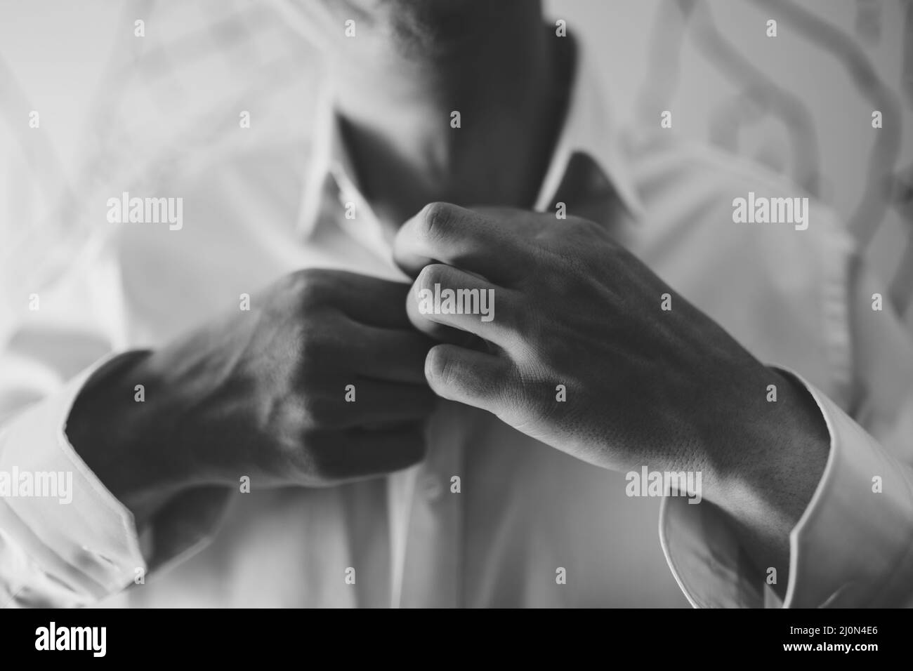 Man is buttoning the buttons on a white shirt. Close-up. Black and white photo Stock Photo