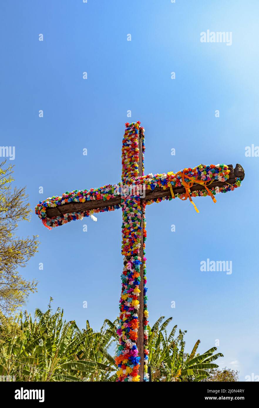 Crucifix decorated with flowers with blue sky in the background Stock Photo